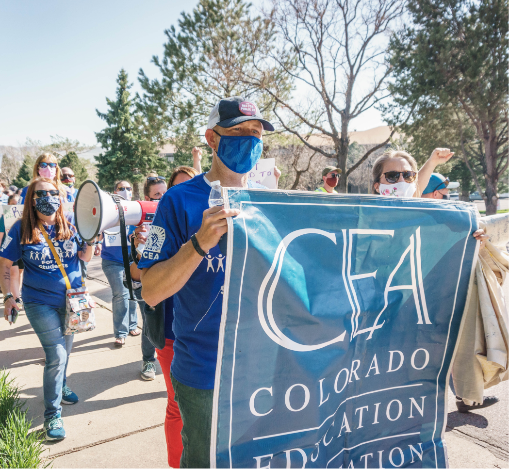 Photo of Colorado Education Association members carrying a CEA banner at a rally for fair pay and benefits