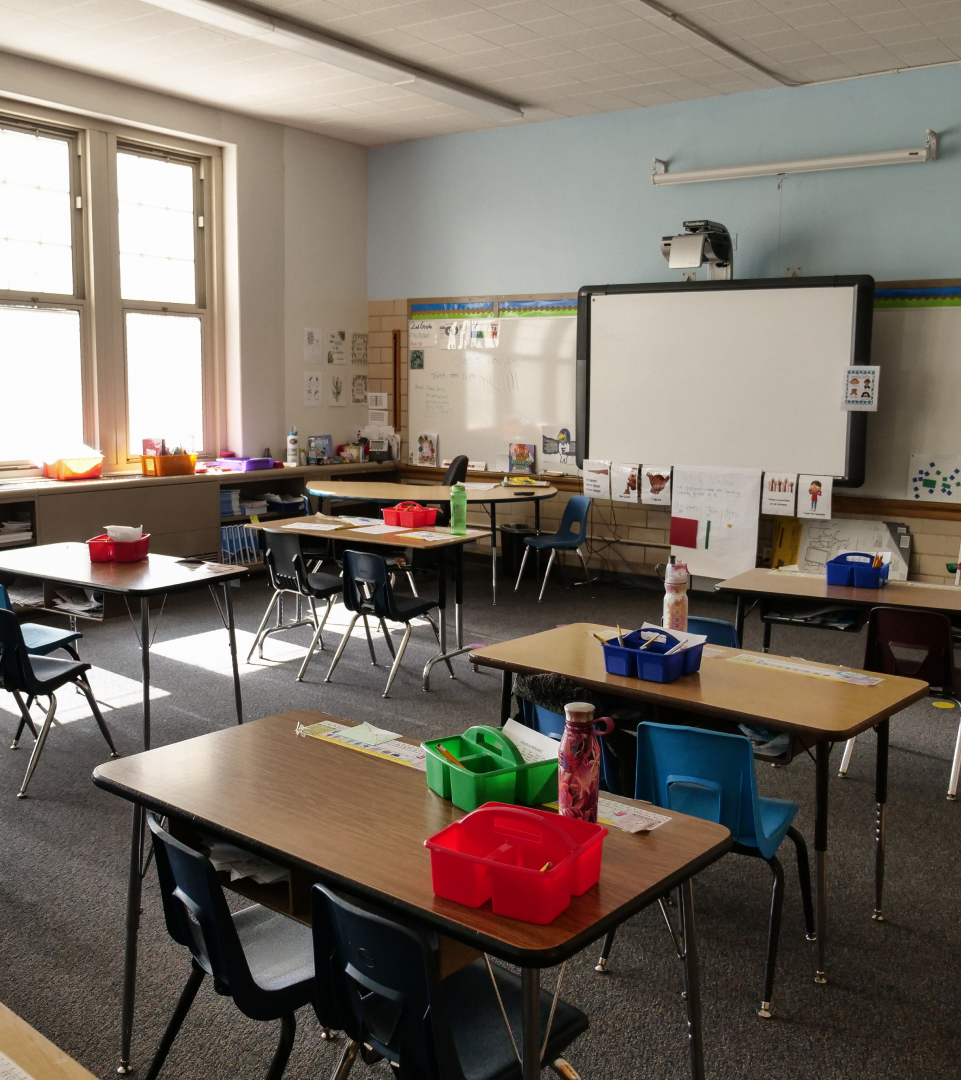 empty classroom photo An empty classroom with student desks, various school supplies on the desk, and lights dimmed